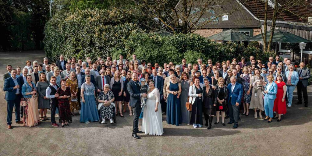 Gruppenfoto mit Brautpaar, kleinem Sohn und allen Hochzeitsgästen vor der Location