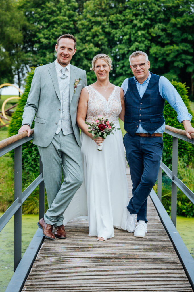 Hochzeitsfotograf Stefan Bröker lächelnd mit einem Brautpaar im Grünen